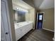 Bathroom featuring a double sink vanity with white cabinets and dark wood-look floors at 7036 Barlows Knoll St, Raleigh, NC 27610