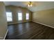 Spacious bedroom featuring a vaulted ceiling, dark wood-look floors, and three bright windows at 7036 Barlows Knoll St, Raleigh, NC 27610