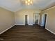 Open bedroom with vaulted ceiling featuring dark wood-look floors and multiple doorways for easy access at 7036 Barlows Knoll St, Raleigh, NC 27610