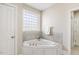 Bright bathroom featuring a corner tub with tile surround and a frosted window at 75 Morgan Dr, Lillington, NC 27546