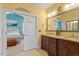 Bright bathroom featuring double vanity with granite countertop and doorway leading to the primary bedroom at 836 Canyoncreek Ln, Fuquay Varina, NC 27526