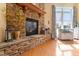 Detailed view of the stone fireplace with wooden mantel, and light filled window in a comfortable room at 836 Canyoncreek Ln, Fuquay Varina, NC 27526