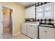 Bright laundry room with washer, dryer, sink, storage cabinets, and stylish wallpaper accent at 836 Canyoncreek Ln, Fuquay Varina, NC 27526