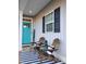 Inviting front porch with rocking chairs, black and white striped rug, and a vibrant teal door at 103 1St St, Haw River, NC 27258