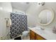 Cozy bathroom with patterned shower curtain, single sink vanity and a round mirror at 12409 Village Gate Way, Raleigh, NC 27614
