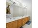 A bright bathroom features a double vanity with a large mirror and wooden cabinets at 12409 Village Gate Way, Raleigh, NC 27614