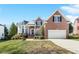Charming two-story brick home with manicured lawn and attached two car garage at 12409 Village Gate Way, Raleigh, NC 27614