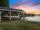 Boat dock featuring a covered slip, boat lift, and stunning lake views at sunset at 1315 Sagamore Dr, Louisburg, NC 27549