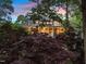 The home's warm exterior glows from within, framed by trees, with a peek at the inviting screened porch at 1315 Sagamore Dr, Louisburg, NC 27549