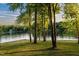 Picturesque lake view framed by lush green trees with a well-maintained grassy lawn in the foreground at 1315 Sagamore Dr, Louisburg, NC 27549
