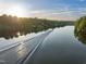 Lake view showcases a boat gliding across the calm water, surrounded by lush trees under a sunny sky at 1315 Sagamore Dr, Louisburg, NC 27549