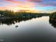 Aerial lake view with a boat on the water, surrounded by lush trees under a vibrant sunset sky at 1315 Sagamore Dr, Louisburg, NC 27549