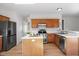 Open kitchen with stainless steel fridge, island, wood cabinets, and laminate floor at 205 Caniff Ln, Cary, NC 27519