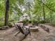 Beautiful backyard featuring a stone fire pit with chairs, surrounded by lush greenery and trees at 2617 Jones Ferry Rd, Chapel Hill, NC 27516