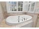 Bathroom featuring a large soaking tub, shuttered window, and tile surround at 2617 Jones Ferry Rd, Chapel Hill, NC 27516