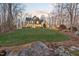 Exterior shot of the home on a grassy hill with trees, showcasing its architectural details at twilight at 2617 Jones Ferry Rd, Chapel Hill, NC 27516