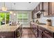Well-lit kitchen with granite countertops, dark cabinets, and a window overlooking the backyard at 428 Morgan Ridge Rd, Holly Springs, NC 27540