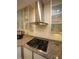 Kitchen detail with gas cooktop, granite countertops, glass cabinets, and stainless steel hood at 4332 Blossom Hill Ct, Raleigh, NC 27613