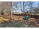 This spacious backyard features mature trees, a swing set, and a private wooden fence at 4711 Marena Pl, Durham, NC 27707