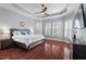 Main bedroom featuring a tray ceiling, ceiling fan, and large windows with shutters at 4711 Marena Pl, Durham, NC 27707