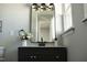 Stylish powder room features a dark vanity cabinet, brushed gold light fixture and modern decor at 5845 Farmwell Road Rd, Raleigh, NC 27610