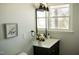 This powder room features a black vanity cabinet, brushed gold light fixture, modern decor, and fresh paint at 5845 Farmwell Road Rd, Raleigh, NC 27610