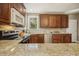 Bright kitchen featuring granite countertops, stainless steel appliances, stone backsplash, and rich wood cabinetry at 6108 King Croydon Ct, Raleigh, NC 27603