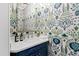Charming powder room featuring vibrant floral wallpaper, marble countertop, and a stylish blue vanity at 620 Marlowe Rd, Raleigh, NC 27609