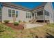 Exterior view of the backyard patio, screened-in porch, and landscaping of the home at 65 Walking Trl, Youngsville, NC 27596