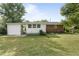 Well-maintained backyard with lush lawn, mature trees, and a mix of brick and white siding on the house at 709 Fitzgerald Dr, Raleigh, NC 27610