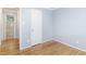 Bedroom with hardwood floors, light blue walls, white door and trim, and doorway to bathroom with tiled shower/tub combo at 709 Fitzgerald Dr, Raleigh, NC 27610