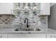 Close up of kitchen sink with grey backsplash, granite countertops, and matte black faucet at 709 Fitzgerald Dr, Raleigh, NC 27610