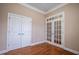 Neutral bedroom with hardwood floors, white trim, closet, and glass paneled door at 804 Long Meadows Rd, Chapel Hill, NC 27516