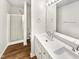 Well-lit bathroom with double vanity, wood-look floors, and glass door shower at 8425 Fawncrest Dr, Raleigh, NC 27603