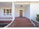 Covered front porch with brick steps and white railings. The orange door provides a pop of color at 905 N Hyde Park Ave, Durham, NC 27701