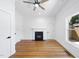 Living room featuring hardwood floors, a fireplace, a modern ceiling fan, and large windows at 905 N Hyde Park Ave, Durham, NC 27701
