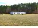 View of the home on a large lot with a treeline in the background at 9115 Nc 157, Rougemont, NC 27572