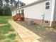 Image of the exterior of the home with a stone sidewalk leading to a wooden deck and gray siding at 9115 Nc 157, Rougemont, NC 27572