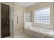 Luxurious bathroom showcasing a glass-enclosed shower, soaking tub, and decorative window at 9413 Lake Villa Way, Raleigh, NC 27614