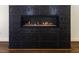 Close-up on a contemporary fireplace with textured, glossy black tile surround and a glass-enclosed firebox at 9413 Lake Villa Way, Raleigh, NC 27614