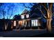 Beautiful two-story home, illuminated at dusk with landscape lighting and mature trees at 100 Tavernelle Pl, Cary, NC 27519