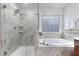 Bright bathroom showcases a glass shower, soaking tub, and neutral stone tile at 104 Red Bark Ct, Apex, NC 27539