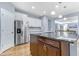 Spacious kitchen with stainless steel refrigerator, island with sink, and hardwood flooring at 104 Red Bark Ct, Apex, NC 27539