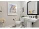 Modern half-bath featuring a pedestal sink, decorative mirror, and stylish accents at 104 Sage Oak Ln, Holly Springs, NC 27540