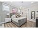 Charming main bedroom with paneled accent wall, ample windows, plush bedding, and a view into ensuite bathroom at 104 Sage Oak Ln, Holly Springs, NC 27540
