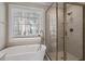 Bright bathroom featuring a modern tub with a shower and separate glass-enclosed shower at 104 Somerset Farm Dr, Holly Springs, NC 27540