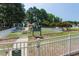 Community playground with swing set, slide, and climbing features enclosed by a white picket fence at 108 Finnway Ln, Cary, NC 27519