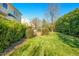 Expansive backyard featuring a well-maintained lawn, lush landscaping, and a cozy stone patio at 1109 Frenchurch Way, Apex, NC 27502