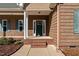 A welcoming front porch with brick steps and columns, complemented by landscaped shrubbery at 121 Starlight Dr, Lillington, NC 27546