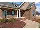 A welcoming front porch with brick steps and columns, complemented by landscaped shrubbery at 121 Starlight Dr, Lillington, NC 27546